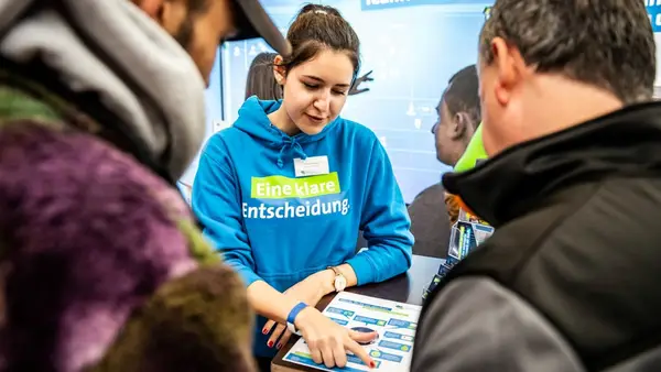 Personen lassen sich am Messestand beraten